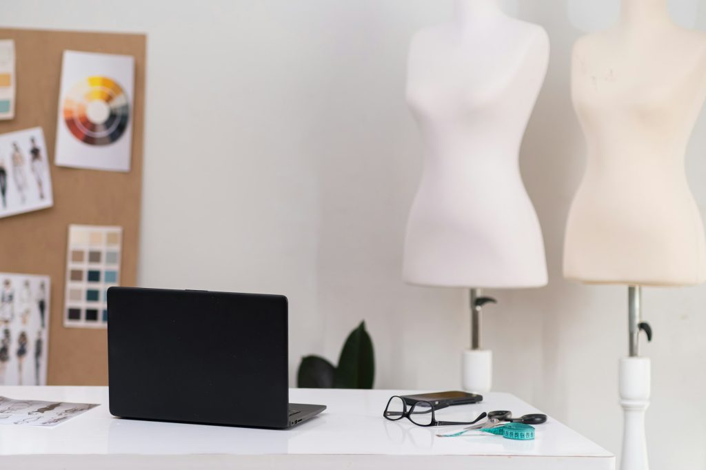 Clothes designer workplace with laptop in dressmaking shop notebook computer on desk in atelier